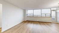Located on the 18th floor at 185 Shaughnessy Blvd in Toronto's Don Mills neighbourhood, this well-appointed one-bedroom, one-bathroom unit offers a bright and functional layout across a single floor. Light wood flooring runs throughout the main living areas, lending a warm, clean aesthetic that complements the crisp white walls.

The spacious living room is a standout feature, anchored by a wide bank of floor-to-ceiling windows that frame sweeping panoramic views of the Toronto skyline and surrounding cityscape. Generous natural light fills the room throughout the day. A separate dining area connects seamlessly to the living space, creating an open and versatile layout.

The galley-style kitchen is efficiently designed with white cabinetry featuring gold-toned hardware, tile backsplash, stone countertops, a double stainless steel sink, and white appliances. A pass-through view into the living area enhances the sense of openness.

The bedroom is a comfortable, well-proportioned space with its own window offering city views, wood flooring, and a built-in sliding-door closet. The bathroom is finished with clean white tile surrounding a full soaker tub and shower combination. A dedicated entrance hallway and additional storage areas complete this thoughtfully organized unit.