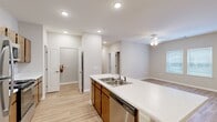This single-story unit in Union City, GA offers a thoughtfully designed open-concept layout that connects the kitchen and living area into one cohesive, comfortable space. The kitchen serves as a functional centerpiece, featuring a large island with a double stainless steel sink and light stone-finish countertops, warm-toned wood cabinetry, and a full suite of stainless steel appliances including a refrigerator, range, microwave, and dishwasher. Recessed lighting illuminates the space cleanly throughout.

The living area is bright and open, with light wood-style flooring, a ceiling fan with light fixture, neutral walls, and a window that allows natural light to filter in. The bedroom is a comfortable size, finished with plush carpet, double closet doors opening to a built-in shelving system, and windows for natural light. The bathroom includes a vanity with matching cabinetry and a walk-in shower. A dedicated laundry room accommodates a full-size washer and dryer side by side. Clean finishes, consistent flooring, and a neutral color palette give the space a modern, move-in-ready feel.