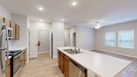 This single-story unit in Union City, GA offers a thoughtfully designed open-concept layout that connects the kitchen and living area into one cohesive, comfortable space. The kitchen serves as a functional centerpiece, featuring a large island with a double stainless steel sink and light stone-finish countertops, warm-toned wood cabinetry, and a full suite of stainless steel appliances including a refrigerator, range, microwave, and dishwasher. Recessed lighting illuminates the space cleanly throughout.

The living area is bright and open, with light wood-style flooring, a ceiling fan with light fixture, neutral walls, and a window that allows natural light to filter in. The bedroom is a comfortable size, finished with plush carpet, double closet doors opening to a built-in shelving system, and windows for natural light. The bathroom includes a vanity with matching cabinetry and a walk-in shower. A dedicated laundry room accommodates a full-size washer and dryer side by side. Clean finishes, consistent flooring, and a neutral color palette give the space a modern, move-in-ready feel.
