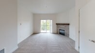 Located in Lacey, WA, this single-floor, three-bedroom, two-bathroom home offers a thoughtfully designed layout with clean, neutral finishes throughout. The living room serves as the heart of the space, featuring plush carpeting, a tile-surround fireplace with a warm wood mantel, and sliding glass doors that open to a private balcony overlooking lush greenery — bringing in abundant natural light and pleasant outdoor views. The kitchen is a standout, outfitted with rich dark wood cabinetry, white countertops, stainless steel appliances including a refrigerator, range, and built-in microwave, and a central island. Wood-look flooring grounds the kitchen area, which flows seamlessly into the adjacent living space, complete with a ceiling fan overhead. The three bedrooms are carpeted and bright, with the primary bedroom offering generous proportions. Additional bedrooms feature windows with natural light and baseboard heating. Both bathrooms are finished in a clean, modern style, each with a full tub-shower combination; one features a rich wood-toned vanity with white countertops and wood-look flooring. The overall aesthetic is fresh and contemporary, presenting a well-maintained, move-in ready home.