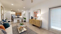 This thoughtfully designed one-bedroom, one-bathroom residence in Leander, TX offers a cohesive open-concept layout with light wood-style flooring flowing through the main living areas. The welcoming entryway features a large window that fills the space with natural light and leads directly into the open living room. The living area is bright and airy, anchored by a ceiling fan overhead and seamlessly connected to the kitchen and dining space. The kitchen is a standout feature, equipped with stainless steel appliances including a side-by-side refrigerator, microwave, and range, complemented by warm wood cabinetry, a tile backsplash, and a granite-topped island with bar seating—ideal for casual dining and entertaining. A hallway connects the main living area to the private bedroom, which is carpeted for comfort and features a window with natural light, a closet, and direct access to the full bathroom. The bathroom is well-appointed with a wood vanity cabinet, granite countertop, and an illuminated mirror. The space also includes a dedicated closet for additional storage. Clean white walls and recessed lighting throughout create a bright, modern ambiance well-suited for comfortable everyday living.
