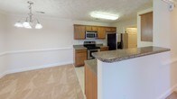 Located at 1916 Rayconda Rd in Fayetteville, NC, this single-floor home offers a practical and comfortable layout designed for everyday living. The open-concept kitchen and living area serve as the heart of the home, where warm-toned wood cabinetry, granite-style countertops, and stainless steel appliances — including a range, microwave, and refrigerator — are complemented by a peninsula breakfast bar that seamlessly connects to the carpeted living space. A chandelier and crown molding add a touch of refinement to the dining and living areas, while a front entry door with glass panels allows natural light to filter in. Throughout the bedrooms, soft wall-to-wall carpeting, ceiling fans with light kits, and windows with blinds create a comfortable and well-ventilated atmosphere. The bathrooms feature large-format tile flooring, rich wood-toned vanity cabinetry with white countertops, and well-lit mirrors, with one bathroom offering a full tub/shower combination. A textured ceiling treatment is consistent throughout the home, adding subtle character. The overall ambiance is clean, neutral, and move-in ready.