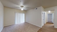 This single-floor residence offers a functional and comfortable layout designed for everyday living. The main living area is generously proportioned, featuring soft wall-to-wall carpet, a ceiling fan with integrated lighting, and a full-width sliding glass door dressed with vertical blinds that invites natural light while providing access to the outdoors. The transition from carpet to wood-look flooring marks the entry into the kitchen and adjoining areas.

The galley-style kitchen is efficiently arranged with warm oak cabinetry lining both sides, light countertops, a double basin sink, and white appliances including a refrigerator, dishwasher, stove, and microwave. A peninsula counter with an overhead opening connects the kitchen to the dining and living areas, enhancing the open flow of the space.

Adjacent to the main living zone is a built-in shelving unit and a dedicated workspace nook, adding a thoughtful organizational feature to the layout. The bedrooms are carpeted and well-sized, offering ample wall space and multiple electrical outlets.

The bathrooms are finished with oak vanity cabinetry, light countertops, large mirrors, and wood-look flooring. One bathroom features a tub-shower combination with white tile surround and overhead storage cabinetry, while another offers an extended vanity with separated water closet, providing added privacy and convenience.
