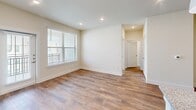 Located at 14119 Montfort Dr in Dallas, TX, this single-story residence offers a thoughtfully designed layout across a comfortable footprint. The open-concept living and kitchen area serves as the heart of the home, featuring warm wood-look flooring, recessed lighting, and a large window with a sliding glass door that fills the space with natural light. The kitchen is outfitted with crisp white shaker cabinetry, granite countertops, a central island with an undermount sink and pendant lighting, and a full suite of stainless steel appliances including a French door refrigerator, built-in microwave, and range. The bedroom is a serene retreat with plush carpet, a ceiling fan, and a bright window overlooking the exterior. It includes access to a walk-in closet and a dedicated en-suite bathroom. Both bathrooms are finished with granite-topped white vanities, wood-look flooring, and tiled tub-shower combinations. Additional closets provide generous storage throughout, and a dedicated laundry area adds everyday convenience. The neutral color palette and clean, modern aesthetic create a bright and welcoming ambiance throughout the entire residence.