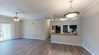 Located at 2500 Club Grove Ln in Cary, NC, this single-floor residence offers a well-designed layout that balances functionality and comfort. The open-concept living and kitchen area serves as the heart of the home, featuring rich wood-look flooring, crown molding, and a pendant light fixture that anchors the space. The kitchen is outfitted with dark espresso cabinetry, granite-style countertops, stainless steel appliances including a refrigerator, electric range, over-the-range microwave, and dishwasher, as well as a peninsula with a built-in sink that opens to the living area. The bedrooms are carpeted for comfort and equipped with ceiling fans. One bedroom features sliding glass doors leading to a private balcony with outdoor views of surrounding greenery. A spacious walk-in closet with wire shelving provides generous storage. The bathroom includes a tiled tub-shower combination, wood-look flooring, a dark-toned vanity, and clean white fixtures. The attached garage offers additional storage and convenient direct interior access, completing this thoughtfully appointed single-level home.