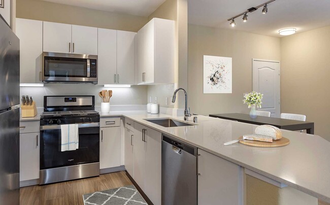 Renovated Package I kitchens with light grey quartz countertops, new white cabinetry, stainless steel appliances, upgraded fixtures, and hard surface flooring throughout - Avalon Camarillo