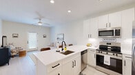 Located at 1151 GA Highway 96 in Kathleen, GA, this single-floor, one-bedroom, one-bathroom home offers a well-designed open-concept layout that maximizes every square foot. Light-colored luxury vinyl plank flooring runs throughout, lending a clean, cohesive look to the entire space.

The kitchen is a standout feature, showcasing white shaker cabinetry with matte black hardware, a white quartz peninsula with bar seating for three, a subway tile backsplash, and a full suite of stainless steel appliances including a range, built-in microwave, dishwasher, and French door refrigerator. The peninsula sink with a matte black faucet adds both style and function.

The living room flows directly from the kitchen and receives natural light through a glass-panel exterior door fitted with blinds. A ceiling fan overhead and light neutral walls contribute to an airy, comfortable atmosphere.

The bedroom is a quiet retreat with a ceiling fan, a window with natural light, and ample room for furnishings. A dedicated laundry room includes wire shelving overhead and hookups for a full-size washer and dryer.

The bathroom features a tub/shower combination with clean white subway tile surround. A hallway connects all areas efficiently, completing this thoughtfully planned home.