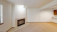 Located at 1810 N 107th St in Seattle, WA, this one-bedroom, one-bathroom unit offers a well-organized single-floor layout that makes efficient use of its space. A welcoming hallway with light wood flooring leads into the main living areas, setting a clean and neutral tone throughout.

The living room is a standout feature, offering plush carpeting, soft neutral walls, and a tile-surround fireplace that serves as a natural focal point. A sliding glass door fills the room with natural light and provides direct access to a private balcony, where views of surrounding greenery add a serene touch.

The kitchen is functional and well-appointed, featuring warm honey-toned wood cabinetry, white countertops, and a full suite of appliances including an electric range. An adjacent dining area provides a natural flow for everyday living and entertaining.

The bedroom is a comfortable retreat with carpet flooring, a window overlooking lush tree canopy, and access to a dedicated closet. An additional closet elsewhere in the unit offers further storage flexibility, along with in-unit laundry for added convenience.

The bathroom is clean and straightforward, with a tub/shower combo featuring tile surround, wood-tone vanity, and light wood flooring. The overall design is practical, understated, and move-in ready.