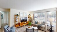 This single-floor residence offers a thoughtfully designed layout with a warm, contemporary aesthetic carried throughout each space. The living room serves as a central gathering area, featuring light hardwood-style flooring, a tile-surround fireplace with a classic white mantel, and generous windows fitted with blinds that invite natural light while maintaining privacy. Framed artwork and mid-century modern furnishings enhance the inviting atmosphere.

The kitchen is outfitted with white cabinetry, quartz-toned countertops, stainless steel appliances including an electric range and dishwasher, a deep undermount sink, and track lighting overhead. An adjoining dining area accommodates a full dining set beneath a pendant drum light fixture, with a sliding door adding flexibility to the space.

The bedrooms are well-proportioned, each with light-toned walls, hardwood-style flooring, and windows that bring in natural light. The primary bedroom offers ample space for a full furniture arrangement. The primary bathroom features a dual-sink vanity with grey countertops, white cabinetry, abundant built-in storage, and a tub-shower combination. A secondary bathroom provides a clean, functional layout with a tub-shower and single vanity.