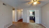 This single-floor residence offers a practical and comfortable layout designed for everyday living. The spacious living area is finished with plush carpeting and features a ceiling fan with light fixture, textured ceilings, and a sliding glass door that invites natural light and provides outdoor access. Neutral-toned walls throughout create a clean, cohesive aesthetic.

The entryway includes a louvered closet for convenient storage and transitions seamlessly into the main living space. The kitchen is well-equipped, showcasing rich dark cabinetry with decorative detailing, granite-style countertops, a double-basin sink, and black appliances including a dishwasher and electric range. Wood-look flooring adds warmth and durability to the kitchen area.

The residence includes two carpeted bedrooms, each outfitted with a ceiling fan and a window fitted with blinds that provide natural light and privacy. The bathroom is cleanly appointed with a white vanity, a large mirror, over-toilet cabinetry for added storage, and a shower-tub combination. Wood-look flooring continues into the bathroom, maintaining a consistent design language throughout the home. The overall ambiance is functional, tidy, and move-in ready.