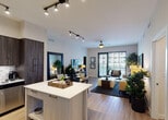 Located at 6600 Main St in Miami Lakes, Florida, this well-appointed single-floor residence offers a thoughtfully designed open-concept layout with contemporary finishes throughout. The living area is bright and inviting, featuring wood-look flooring, track lighting, a ceiling fan, and large sliding glass doors that open to an outdoor balcony, allowing abundant natural light and outdoor views to flow into the space.

The kitchen is a standout feature, showcasing rich dark wood cabinetry that extends to the ceiling, a classic tile backsplash, stainless steel appliances including a refrigerator, range, microwave, and dishwasher, and a white quartz-topped island with bar seating — ideal for casual dining. Adjacent to the kitchen, a dedicated dining area provides additional space for entertaining.

The bedrooms are generously sized with plush carpet flooring, ceiling fans, and ample natural light from well-dressed windows. The primary bedroom includes a walk-in closet with built-in shelving. The primary bathroom features a dual-sink vanity with wood cabinetry, a soaking tub, and a separate glass-enclosed shower. A second full bathroom offers a soaking tub with a tiled surround, wood-look flooring, and a single vanity. The overall ambiance is modern, warm, and cohesive throughout.