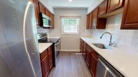 Located at 20 Max Dr in Morris Plains, NJ, this single-floor residence offers a thoughtfully updated interior with a clean, modern aesthetic throughout. The kitchen serves as a functional centerpiece, showcasing rich cherry-toned cabinetry, light quartz countertops, and a classic white subway tile backsplash. Stainless steel appliances—including a range, over-the-range microwave, refrigerator, and dishwasher—complement the space, while a window above the sink area brings in natural light and views of surrounding greenery. Wood-style plank flooring runs throughout, providing a cohesive look across all living areas.

The living area is open and well-lit, with recessed lighting and a large window that draws in abundant natural light. A separate bedroom offers a quieter retreat, featuring dual windows that overlook the outdoors and ample closet storage with multiple panel doors. Notably, an in-unit stacked washer and dryer is conveniently housed within the bedroom area. The bathroom is finished with light tile flooring, a vanity, and a full tub with a window providing ventilation and natural light. Additional utility areas connect the main living spaces, completing this well-organized and move-in-ready residence.