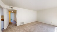 Located at 2950 W Portage Bay Ave in Davis, CA, this two-bedroom, two-bathroom single-floor unit offers a practical and well-organized layout. The kitchen features white cabinetry, tan laminate countertops, a gas range, stainless steel sink, and light wood-look flooring. A pass-through counter opens directly to the living area, enhancing the sense of connectivity. The living room is generously sized, with plush carpeting, a large window fitted with vertical blinds that allow ample natural light, and a built-in shelving unit that adds functional character to the space. A hallway connects the main living areas to both bedrooms and bathrooms. The spacious primary bedroom features large windows with outdoor views and soft carpeting. The second bedroom is similarly well-proportioned, also with carpeting and a window. Both bathrooms are cleanly designed; one includes a shower-tub combination with sliding glass doors and wood-look tile flooring, while the other features a vanity with tan countertop, under-sink cabinet storage, and a large mirror. The unit's neutral color palette and consistent finishes throughout create a cohesive, move-in-ready atmosphere.