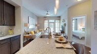 Located at 400 Belmont, this single-floor residence offers a thoughtfully designed layout with modern finishes and a cohesive aesthetic throughout. The open-concept kitchen is a standout feature, showcasing rich dark-wood cabinetry extending to the ceiling, stainless steel appliances including a refrigerator, range, and built-in microwave, granite countertops, a tile backsplash, and a central island with a undermount sink and pendant lighting overhead. Track lighting and ceiling-mounted fixtures provide layered illumination throughout the living and kitchen areas. The spacious living area flows naturally from the kitchen and features durable hardwood-style flooring, a ceiling fan, and windows that invite natural light. A well-proportioned hallway connects the living spaces to the private areas of the home, where bedrooms feature plush wall-to-wall carpeting, large windows with exterior views, and access to walk-in closets. The bathroom is finished with a tiled tub-surround, hardwood-style flooring, dark vanity cabinetry, and granite countertops, maintaining design consistency with the rest of the home. White panel doors, clean baseboards, and neutral wall tones contribute to a bright, polished ambiance throughout.