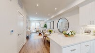 This well-designed two-floor residence offers a seamless blend of modern aesthetics and functional living. The open-concept main level immediately impresses with light hardwood flooring that flows throughout, recessed lighting, and a bright, airy atmosphere. The kitchen is a standout feature, outfitted with white shaker cabinetry, a classic subway tile backsplash, quartz countertops, and a full suite of stainless steel appliances including a range, over-the-range microwave, dishwasher, and refrigerator. A peninsula provides additional counter space and connects effortlessly to the dining area, which is anchored by a round marble-top table and a striking circular wall mirror. The living area is warmly inviting, with French doors that allow natural light to pour in. Bedrooms are generously proportioned, featuring plush carpeting, multiple windows with slatted blinds, and ample closet space. The primary bedroom offers a serene retreat with warm neutral tones and generous natural light. Bathrooms are thoughtfully finished, one showcasing a full tub-shower combination with white tile surround, and another featuring a stylish hexagonal black-and-white tile floor with a clean white vanity — adding a timeless design touch throughout.