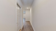 This two-story, 2-bedroom, 2-bathroom home offers a thoughtfully designed layout spread across two floors. The main level features an open-concept living area with recessed lighting and durable hardwood-style flooring that flows seamlessly throughout. The kitchen is a standout, equipped with crisp white shaker cabinetry, light quartz countertops, a subway tile backsplash, stainless steel appliances including a refrigerator, electric range, and built-in microwave, and a peninsula with an undermount sink and pendant lighting above — ideal for both cooking and casual dining.

A clean, well-lit hallway with recessed lighting and the same consistent flooring connects the main living areas. The upper floor houses the bedrooms, including a generously sized primary bedroom with a ceiling fan, ample natural light from a large window, and dual closets providing excellent storage. The second bedroom also features a ceiling fan and access to natural light. Both bathrooms are finished with tile flooring, dark wood vanities, white quartz countertops, and a tub-shower combination. Throughout the home, neutral tones, white panel doors, and clean lines create a modern, move-in-ready aesthetic.