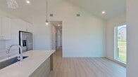 This 630-square-foot, single-story home in Rowlett, TX offers a well-designed 2-bedroom, 2-bathroom layout with modern finishes throughout. The kitchen is a standout feature, boasting vaulted ceilings, pendant lighting, a large center island with a quartz countertop and undermount sink, white shaker cabinets, subway tile backsplash, and stainless steel appliances including a refrigerator, range, and microwave. Light wood-look flooring and a large window flood the space with natural light and outdoor views. The primary bedroom spans 120 square feet with plush carpeting and ceiling fan. The second bedroom mirrors this comfort, featuring corner windows that offer abundant natural light and neighborhood views. The primary bathroom includes a glass-enclosed walk-in shower with subway tile surround, wood-look flooring, and a white vanity with quartz countertop. The second bathroom features a full soaking tub with a tiled surround, chrome fixtures, and matching flooring. A hallway connects the bedrooms and bathrooms, completing this efficient and contemporary floor plan.