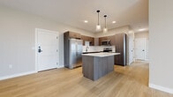 Located at 4328 Provision Pky in Fort Wayne, Indiana, this modern single-floor unit offers a clean, contemporary design with light wood-style flooring running throughout every room, creating a cohesive and polished aesthetic.

The kitchen serves as a standout feature, equipped with dark wood cabinetry, a subway tile backsplash, stainless steel appliances including a refrigerator, range, and microwave, and a central island with a crisp white countertop. Pendant lights hang above the island, adding a stylish finishing touch. The open layout of the kitchen connects naturally to the main living area, promoting a seamless flow between spaces.

The living area is bright and spacious, benefiting from large black-framed windows and a full sliding glass door that opens to an outdoor balcony, allowing generous natural light and views of the surrounding community. The neutral wall tones complement the light flooring and contribute to a calm, inviting atmosphere.

Bedrooms are well-proportioned with large windows that bring in additional natural light and views of the outdoors. Storage is well-addressed with a dedicated closet featuring double doors and built-in shelving. The entryway is open and welcoming, with clean white panel doors and modern hardware carried consistently throughout the unit.
