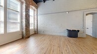 Located at 810 Monocacy St in Bethlehem, PA, this one-bedroom, one-bathroom unit showcases a striking fusion of historic industrial character and contemporary design. The open-concept living and kitchen area immediately impresses with soaring ceilings, exposed painted brick walls, and warm light hardwood flooring throughout. A dramatic arched brick doorway serves as a standout architectural element, framing large windows that flood the space with abundant natural light.

The kitchen is well-appointed with gray shaker-style cabinetry, stone-look countertops, a geometric tile backsplash, and a full suite of stainless steel appliances including a refrigerator, range, microwave, and dishwasher. Exposed ductwork and a sputnik-style pendant light fixture add to the loft-inspired aesthetic. Industrial conduit piping runs along the painted brick walls, further emphasizing the building's historic character.

The bedroom features painted brick walls, soaring ceilings, and closet space, maintaining the unit's cohesive industrial aesthetic. The bathroom is clean and functional, offering a combination tub and shower, with an adjacent closet area equipped with wire shelving for additional storage. Light hardwood flooring ties all rooms together seamlessly.