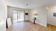This efficient one-bedroom, one-bathroom unit is thoughtfully organized across a single floor, offering a practical layout that makes the most of its compact footprint. The living room is bright and welcoming, finished with light wood-style flooring and neutral walls beneath a textured ceiling. A wall-mounted air conditioning unit provides climate control, while a sliding glass door opens directly onto a private enclosed patio, where mature trees and surrounding greenery create a pleasant outdoor retreat.

The kitchen is well-equipped with ample light wood cabinetry spanning floor to ceiling, offering generous storage. A stainless steel gas range sits beneath an overhead ventilation hood, complemented by light-toned countertops that provide functional prep space. The wood-style flooring carries seamlessly throughout.

The bedroom is a quiet, clean space with a window framing views of lush outdoor greenery, allowing natural light to filter in through vertical blinds. A closet and hallway round out the layout, adding practical storage and connectivity between rooms.

The full bathroom features a shower-tub combination with a curved rod, clean white fixtures, wood-style flooring, and a towel bar with brushed nickel finishes. Throughout the unit, the consistent flooring, neutral palette, and functional design elements create a cohesive and livable environment.