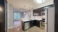 Located at 1638 Franklin Ave in the heart of Los Angeles, CA, this efficiently designed single-floor unit offers a thoughtful layout comprising a living room, kitchen, bathroom, and closet. The open-concept kitchen is a standout feature, showcasing dark espresso cabinetry with sleek hardware, white quartz countertops, a subway tile backsplash, and a full suite of stainless steel appliances including a gas range, built-in microwave, dishwasher, and refrigerator. Pendant lighting and a flush-mount ceiling fixture illuminate the space with a modern touch. A peninsula counter connects the kitchen to the living area, creating a seamless flow ideal for entertaining. The living room is bright and airy, featuring warm hardwood flooring, soft neutral-toned walls, a ceiling fan, and a set of French doors fitted with blinds that invite natural light while offering privacy. An additional window further enhances the openness of the room. The bathroom is finished with clean tile flooring and crisp white walls, maintaining the unit's consistent modern aesthetic. A dedicated closet with built-in shelving provides convenient storage. A smart thermostat is also present, adding a layer of modern convenience to this well-designed Los Angeles residence.