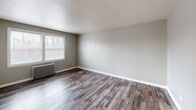 Located at 415 E 222nd St in Euclid, Ohio, this single-floor unit offers a practical and comfortable layout across two bedrooms, one bathroom, a kitchen, and connecting hallways. The spacious primary bedroom features rich, dark wood-look vinyl plank flooring, neutral gray walls, a bright window with blinds, and a classic cast-iron radiator, providing both character and efficient heating. The second bedroom is carpeted in light neutral tones and includes a closet with a paneled door alongside direct hallway access, keeping the layout well-connected. The kitchen is equipped with white shaker-style cabinetry, granite-look countertops, a stainless steel gas range, and a window overlooking the exterior — all set atop the same durable wood-look flooring that carries through the main living areas. The bathroom is clean and functional, featuring a white tub-shower combo, a white vanity with brushed nickel fixtures, tile wainscoting, light hardwood-style flooring, and a window that brings in natural light. The overall aesthetic is clean and neutral throughout, with consistent use of light gray and beige tones, white trim, and updated flooring surfaces. Radiator heating is present in multiple rooms, adding a traditional touch to this move-in ready unit.