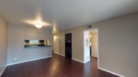 This single-floor residence offers a cohesive and functional layout with rich, dark hardwood flooring running throughout every room, creating a warm and unified aesthetic. The open living area is bright and welcoming, featuring a flush-mount light fixture and a pass-through bar that connects seamlessly to the kitchen. A built-in dark cabinet unit provides additional storage within the living space.

The galley-style kitchen is well-equipped with dark cabinetry on both sides, matching dark granite-style countertops, a full-size refrigerator, an electric range with overhead ventilation, and a sink — all finished in a consistent dark color scheme that gives the kitchen a bold, modern feel.

Multiple bedrooms are present throughout the unit, each featuring dark hardwood flooring, ceiling fans with light fixtures, and generous closet space. One bedroom includes a distinctive arched window that fills the room with natural light, while others offer standard windows with blinds. Closets vary from single to double configurations with built-in shelving.

The bathrooms are appointed with dark vanities topped with granite-style countertops, large mirrors, louvered medicine cabinets, and brushed nickel fixtures, offering a polished and practical finish. The neutral taupe wall tones throughout the residence complement the dark flooring and cabinetry, resulting in a consistent and contemporary interior palette.