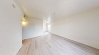 Located at 2125 Las Vegas Boulevard North in North Las Vegas, NV, this one-bedroom, two-bathroom unit offers a practical and efficiently designed single-floor layout. The combined kitchen and living area forms the heart of the unit, with the living space featuring light wood-style flooring, neutral cream walls, and a large window with vertical blinds that allows natural light to fill the room. The kitchen is laid out in a galley style, equipped with dark cabinetry, gray laminate countertops, a double-basin sink, and matching appliances including a range and refrigerator. The bedroom is a comfortable size, finished with plush gray carpet and a window that brings in additional natural light. A dedicated closet provides storage space. Both bathrooms are finished with light wood-style flooring, and one features a dark vanity with gray countertop, a lighted mirror, and a shower-tub combination. The overall color palette throughout the unit is clean and neutral, with white walls and light finishes contributing to a bright and airy ambiance. The unit offers a straightforward, move-in-ready layout suited for efficient everyday living.