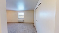Located at 9410 Babcock Blvd in Allison Park, PA, this two-bedroom, one-bathroom unit offers a practical and comfortable single-floor layout. The kitchen is well-equipped with white cabinetry providing ample storage, dark laminate countertops, a double sink, and white appliances including a range and refrigerator. Tile flooring in the kitchen transitions to carpet in the living and bedroom areas, creating a clear delineation between spaces. The primary bedroom is a generously sized room featuring a ceiling fan with light fixture, a large window that allows for natural light, a baseboard heater, and a spacious closet. The second bedroom is similarly carpeted and includes a wall-unit HVAC, a window with an outdoor view, and a built-in closet with bi-fold doors. A hallway connects the main living areas to the full bathroom, which features tile flooring, a white vanity, toilet, and a tub/shower combination with built-in shelving. The unit maintains a clean, neutral color palette throughout, with white walls and trim offering a bright and versatile backdrop. Overall, the layout is efficient and well-organized, making practical use of the available space.