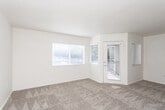 Located at 8870 S State St in Sandy, Utah, this single-floor residence offers a well-organized layout designed for comfortable everyday living. The open living area is generously sized, featuring neutral-toned carpet, soft beige walls, and multiple windows dressed with white blinds that allow an abundance of natural light to fill the space. A private exterior door provides direct outdoor access, enhancing the unit's connectivity to the outside. The updated kitchen is a functional highlight, showcasing white cabinetry, light countertops, wood-look vinyl flooring, and a full suite of stainless steel appliances including a refrigerator, range with double oven, dishwasher, and overhead microwave. The layout includes multiple carpeted bedrooms, each benefiting from natural light via sizable windows. One bedroom features a dedicated walk-in closet, while another includes convenient access to additional rooms through a double-door entry. The bathroom is finished with wood-look flooring, a white vanity with storage, a large mirror with overhead lighting, and a tub-shower combination. Throughout, the clean, neutral palette and well-maintained finishes create a bright, move-in-ready atmosphere suited for a variety of lifestyles.