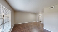 This one-bedroom, one-bathroom unit in Baton Rouge, Louisiana offers a practical and comfortable single-floor layout. The living room serves as the heart of the space, featuring rich dark hardwood-style flooring, neutral beige walls, a textured ceiling, and a large window with blinds that allows natural light to fill the room. The open sightline from the living area leads directly to the kitchen, making the layout feel connected and functional.

The kitchen is a galley-style space with white cabinetry lining both walls, light countertops, a stainless steel sink, a white range, and a refrigerator. A window above the sink provides additional natural light. The kitchen offers ample cabinet storage for everyday needs.

The bedroom is a comfortable retreat with plush wall-to-wall carpeting, a window that brings in natural light, a textured ceiling, and two doors — one leading to a walk-in closet and one to the hallway. The walk-in closet features dual hanging rods and a shelf above, providing well-organized storage space.

The bathroom includes a full tub and shower combo with tiled surround, a vanity with a countertop sink, a toilet, and hardwood-style flooring. A hallway connects all rooms, completing the efficient and well-organized floor plan of this Baton Rouge residence.