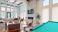 Located at 5 Tree Farm Drive in Carbondale, Colorado, this thoughtfully designed single-floor amenity space offers an impressive blend of modern aesthetics and functional gathering areas set against a scenic mountain backdrop.

The expansive kitchen and living room serves as the heart of the space, anchored by a dramatic floor-to-ceiling stacked stone fireplace with a mounted flat-screen TV above a sleek linear hearth. Soaring ceilings with exposed wood beams add warmth and architectural character, while an abundance of floor-to-ceiling windows and clerestory windows flood the interior with natural light. Light hardwood flooring runs throughout, complementing the contemporary furnishings and a billiard table that adds a recreational touch. The open kitchen features a substantial waterfall-edge marble island with seating for several guests, warm wood cabinetry, stainless steel appliances, open shelving, and a cluster of globe pendant lights overhead.

The dedicated exercise room is generously sized and fully outfitted with cardio equipment including treadmills and ellipticals, free weights, cable machines, weight benches, and floor-to-ceiling mirrors. Bold teal accent walls and bright overhead lighting create an energizing atmosphere, and a compact refreshment station adds convenience.

Large glass doors open directly to an outdoor pool and patio area, framing sweeping views of the surrounding Colorado mountains.