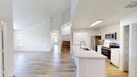 MacAlpine Place Unit 18-308 (C2L) is a 3-bedroom, 2-bathroom residence spanning 1,650 square feet across two floors. The main level comprises 1,240 square feet and includes an open-concept kitchen and living room, a hallway, and two additional rooms. The upper level adds 410 square feet, housing the primary bedroom at 170 square feet. Throughout the home, light wood-style flooring creates a clean, cohesive aesthetic, complemented by crisp white walls and ceiling fans in the bedrooms. The kitchen is a standout feature, equipped with stainless steel appliances including a refrigerator, range, and over-the-range microwave, light wood cabinetry, a large center island with a quartz countertop and undermount sink, and an in-unit washer and dryer. Both bathrooms feature white quartz vanity countertops, undermount sinks, white cabinetry, tub-shower combinations, and wood-style flooring. Natural light flows through multiple windows fitted with horizontal blinds. The unit also includes three closets with wire shelving for ample storage. The staircase connects both levels, completing this well-organized and functional two-story floor plan.