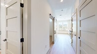Located at 2000 Aspen Way in Franklin, TN, this thoughtfully designed one-bedroom, one-bathroom unit offers a clean, modern aesthetic across a single floor. Light-toned wood flooring runs seamlessly throughout, lending warmth and continuity to every room.

The combined kitchen and living area forms the heart of the unit. The kitchen is well-appointed with white shaker-style cabinetry, white quartz countertops, a classic subway tile backsplash, and a full suite of stainless steel appliances including an electric range, over-the-range microwave, dishwasher, and refrigerator. A window above the sink brings in natural light and outdoor views, enhancing the open feel of the space.

The bedroom is a comfortable, well-proportioned retreat featuring a ceiling fan with light fixture, a large window with blinds, and a double-door shaker-style closet. The room's clean white walls and bright natural light create a calm, airy atmosphere.

The bathroom is finished with a white vanity featuring black hardware, a white countertop, and light wood flooring consistent with the rest of the unit. Shaker-style panel doors with black hardware are featured throughout, adding a cohesive modern-farmhouse design touch. A barn-style sliding door is also present in the hallway, contributing to the unit's distinctive character.
