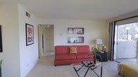 This single-floor residential space offers a comfortable and functional layout designed for everyday living. The living room serves as the heart of the home, featuring wall-to-wall carpeting that adds warmth underfoot and a neutral color palette throughout that creates a calm, inviting atmosphere. A textured ceiling adds subtle visual interest to the space. The room provides ample space for seating and entertaining, with a clear sightline through to a connecting hallway that leads to additional areas of the home, suggesting a well-organized floor plan. Wall space is thoughtfully utilized for artwork display, enhancing the overall aesthetic of the room. A side area offers room for accent furnishings and decorative elements, contributing to the lived-in charm of the space. The open passageway visible from the living area hints at a practical interior flow, connecting the main living space to what appears to be a hallway with access to further rooms. Overall, the space presents a clean, straightforward residential interior with a cozy ambiance, making it a functional and comfortable place to call home.
