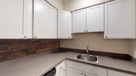 Located at 59 Fitzhenry Blvd in Columbus, Ohio, this two-floor residence offers a well-organized layout with comfortable living spaces throughout. The kitchen is a standout feature, showcasing white shaker-style cabinetry, granite-look countertops, a stainless steel refrigerator, range, and microwave, complemented by a striking exposed brick accent wall that adds warmth and character. Wood-look vinyl flooring grounds the kitchen area, which also benefits from a ceiling fan overhead.

The main living area is bright and open, with plush carpeting and a large sliding glass door fitted with vertical blinds that opens to an outdoor patio, allowing for generous natural light. Additional rooms on both floors feature soft carpeting, ceiling fans, and windows with blinds that bring in natural views of the surrounding greenery. One bedroom includes a spacious walk-in closet with shelving, while another features convenient closet access alongside a dedicated laundry hookup area.

The bathroom is clean and functional, with a full tub-and-shower combo, a white vanity, and wood-look vinyl flooring that ties the space together. Neutral warm-toned walls throughout the home create a cohesive and inviting atmosphere across all rooms and levels.