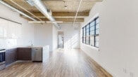 Located at 121 Westmoreland Ave in White Plains, NY, this thoughtfully designed single-floor unit blends industrial aesthetics with modern finishes. The open-concept living and dining area is defined by soaring exposed concrete ceilings with visible wooden beams and ductwork, lending a loft-like character throughout. Large black-framed windows line the main living space, flooding the interior with abundant natural light and offering views of the surrounding cityscape and greenery.

The kitchen is well-appointed with a U-shaped layout featuring two-tone cabinetry — crisp white upper cabinets paired with dark lower units — complemented by a clean quartz countertop, a center island with sink, and a full suite of stainless steel appliances including a refrigerator, range, microwave, and dishwasher.

The bedrooms are generously sized, each benefiting from natural light through black-framed windows, with hardwood-style plank flooring and built-in closet space. The unit includes two bathrooms: one featuring large-format tile flooring and a soaking tub, and a second with sleek gray subway tile in the shower, a wall-mounted sink, and a mirrored medicine cabinet. A hallway with heavy-duty barn-style doors connects the private areas of the unit, completing this stylish and functional living space.