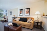 Located in Walnut Creek, CA, this one-bedroom, one-bathroom residence offers a well-organized single-floor layout designed for comfortable everyday living. The open-concept living and dining area is anchored by plush wall-to-wall carpeting, neutral tones, and a cozy fireplace, creating a warm and inviting atmosphere. The living space flows naturally into the dining area, which features hardwood-style flooring and accommodates a dining set with ease.

The kitchen is positioned adjacent to the living area and features a breakfast bar with counter seating, white cabinetry, and modern appliances — making it both functional and easy to access from the main living space.

The bedroom is a comfortable retreat with carpeted flooring, a mirrored sliding-door closet, and direct access to a private balcony overlooking lush, tree-lined surroundings. The outdoor balcony provides a peaceful setting with seating space, bringing in natural greenery and light.

The bathroom is clean and efficiently designed, featuring a combination tub and shower enclosed by sliding glass doors and hardwood-style flooring, maintaining a cohesive aesthetic throughout the home.

Additional storage is provided by two closets, and a hallway connects the main spaces efficiently. The overall ambiance is warm, practical, and well-suited for those seeking a serene living environment in the heart of Walnut Creek.