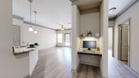 Located at 602 Estuary Trl in Alpharetta, Georgia, this single-floor residence offers a thoughtfully designed open-concept layout finished with light wood-look flooring throughout. The kitchen serves as a central highlight, featuring dark cabinetry paired with contrasting gray lower cabinets, granite countertops, a tile backsplash, stainless steel refrigerator, and a peninsula with pendant lighting that doubles as a breakfast bar. A clever built-in nook with an under-shelf light and granite surface provides a dedicated workspace seamlessly integrated into the layout. The spacious living area flows naturally from the kitchen and is outfitted with crown molding, a ceiling fan, and a glass door that allows natural light to fill the room. Bedrooms are generously sized with neutral walls, wood-look flooring, and access to a large walk-in closet equipped with wire shelving. The bathroom features dark wood cabinetry, a granite-topped vanity, a large mirror, and a tiled shower. Throughout the residence, a neutral color palette, textured ceilings, and consistent flooring create a cohesive and welcoming ambiance suited for comfortable everyday living in the Alpharetta community.