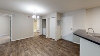 Located at 1545 15th Ave SE in Saint Cloud, Minnesota, this single-floor unit offers a practical and comfortable layout with a clean, updated aesthetic throughout. The open living and dining area features a combination of wood-look plank flooring and plush carpeting, with a textured ceiling and multiple windows that invite natural light and offer views of the surrounding greenery. A wall-mounted air conditioning unit and baseboard heating provide year-round climate control.

The kitchen is well-appointed with crisp white cabinetry, dark countertops, a classic subway tile backsplash, and a full suite of appliances including a stainless electric range, over-the-range microwave, refrigerator, and dishwasher. Wood-look flooring continues through this space, complementing the modern cabinetry hardware.

The bedrooms are carpeted for comfort, each with windows overlooking lush outdoor foliage and baseboard heating. The bathroom includes a full tub-shower surround in a clean, neutral finish. A dedicated entryway area features wood-look flooring, a chandelier light fixture, and convenient in-unit laundry, adding a layer of everyday practicality to this well-maintained Saint Cloud residence.