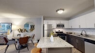 Located at 180 N Jefferson St in Chicago's vibrant West Loop neighborhood, this single-floor residence offers a thoughtfully designed open-concept layout that seamlessly connects the kitchen, dining, and living areas. The kitchen is a standout feature, boasting a large granite-topped island with bar seating, two-tone cabinetry with crisp white upper cabinets and dark lower cabinets, a classic subway tile backsplash, and a full suite of stainless steel appliances including a gas range, microwave, dishwasher, and refrigerator. The open flow from the kitchen leads into a generously sized living and dining area, where light wood-style flooring runs throughout, creating a warm, cohesive aesthetic. The living area is bright and welcoming, anchored by a large window that draws in natural light and frames views of the surrounding Chicago cityscape. The dining area connects naturally to both the kitchen and living space, making the layout ideal for entertaining. The bathroom features a dark wood vanity with a granite countertop, a framed mirror, and light wood-style flooring that complements the rest of the residence. Neutral gray walls and textured ceilings complete the contemporary design, giving the entire space a polished, modern character.