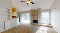 This single-floor residence offers a well-designed layout that blends comfort and functionality throughout. The living room serves as the focal point of the home, showcasing a striking floor-to-ceiling brick fireplace with a raised hearth and a built-in shelving unit to one side. Vaulted ceilings with a ceiling fan add volume and airflow to the space, while sliding glass doors flood the room with natural light and provide direct access to an outdoor patio with surrounding greenery. The adjacent kitchen is equipped with white cabinetry, granite countertops, a stainless steel sink, and a full suite of appliances, complemented by wood-look flooring and a window overlooking the outdoors. A curved breakfast bar connects the kitchen to the living area, enhancing the open-concept feel. The bedrooms are generously sized with plush carpeting and neutral tones; the primary bedroom features vaulted ceilings, a ceiling fan, and ample natural light. Additional bedrooms offer comfortable proportions with textured ceilings. The bathrooms include tiled tub-shower combinations, wood-look flooring, granite-topped vanities, and clean, functional fixtures. Throughout the home, an abundance of natural light and thoughtful design details create a warm and inviting atmosphere.