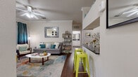 Located in Austin, TX, this generously sized one-bedroom, one-bathroom residence offers a well-designed layout across a single floor. The open-concept living and kitchen area is anchored by rich hardwood-style flooring, crown molding, and a ceiling fan, creating a bright and welcoming atmosphere. Sliding glass doors lead to a private covered balcony overlooking mature trees, providing a peaceful outdoor retreat with wrought iron railing.

The kitchen is well-appointed with stainless steel appliances, including a refrigerator, range, and built-in microwave, complemented by white cabinetry, dark granite-style countertops, and a double-basin sink. The space flows seamlessly into the living area, making it ideal for both everyday living and entertaining.

The spacious bedroom features plush carpeting, a ceiling fan, and a large window that brings in natural light. The full bathroom includes a granite-topped vanity with white cabinetry, a large mirror, and a shower-tub combination. A dedicated closet provides ample storage, and a separate laundry area with a full-size washer and wire shelving adds everyday convenience. Crown molding throughout lends a refined, cohesive finish to the entire residence.