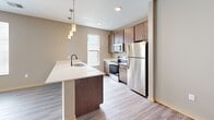 Located at 423 W Mifflin St in Madison, WI, this well-designed one-bedroom, one-bathroom unit offers a thoughtfully planned single-floor layout with a clean, contemporary aesthetic throughout. Light wood-look flooring runs continuously through the space, complementing neutral taupe and gray wall tones that create a calm, cohesive ambiance.

The combined kitchen and living area serves as the heart of the unit. The kitchen is equipped with stainless steel appliances — including a refrigerator, electric range, and built-in microwave — set against dark wood cabinetry and bright white countertops. A peninsula with an undermount sink and stylish pendant lighting provides both additional prep space and a natural division between the kitchen and living area. A window above the sink allows natural light to fill the space.

The living room is generously proportioned, featuring light-filled windows and a glass-panel door that opens to an outdoor area, extending the sense of space. The bedroom is a comfortable size, outfitted with a ceiling fan, a large window with a treetop view, and a double-door closet for ample storage.

The bathroom features a long vanity with dark cabinetry, a white countertop, an undermount sink, a large mirror, and a shower/tub combination — all finished in a consistent modern style that ties the unit together.