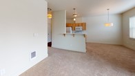This single-floor residence offers a thoughtfully designed layout that balances functionality and comfort. The open-concept living area is carpeted and bathed in natural light, featuring a sliding glass door with vertical blinds that opens to an outdoor space, alongside an additional window that further brightens the room. A peninsula-style breakfast bar connects the living area to the kitchen, making the space feel expansive and cohesive.

The kitchen is well-equipped with warm-toned wood cabinetry, white appliances including a refrigerator, electric range, and over-the-range microwave, and a dual-basin sink set into a light countertop. Hardwood-style flooring runs through the kitchen, providing a clean contrast to the carpeted living and bedroom areas.

The bedrooms are generously proportioned with plush carpeting, neutral wall tones, and windows that allow ample natural light. At least one bedroom includes a walk-in closet with built-in rod storage.

Two full bathrooms serve the unit. One features a combination tub and shower, a wood-toned vanity with a stone-finish countertop, and large-format tile flooring. The second bathroom offers a standalone walk-in shower with a framed glass door, a matching vanity, built-in storage cabinetry, and the same tile flooring, lending a consistent and polished aesthetic throughout.