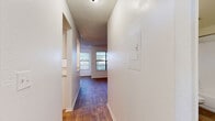 This single-floor residence offers a well-organized layout connected by a central hallway with wood-style flooring, textured ceilings, and clean white walls throughout. The hallway leads to the main living areas, with an electrical panel access point conveniently located along the corridor.

The living room is a standout space, featuring warm wood-style flooring, a white-mantled fireplace, a ceiling fan with light fixture, and large windows fitted with blinds that invite generous natural light and outdoor views. The open feel of this room makes it a comfortable central gathering area.

The kitchen is thoughtfully updated with crisp white cabinetry, light stone-look countertops, and a full suite of stainless steel appliances including a refrigerator, electric range, over-the-range microwave, and dishwasher. A window above the sink adds natural light, while recessed lighting and light wood-style flooring complete the bright, functional space.

The bedroom features soft carpeting, white walls, and a window with blinds offering outdoor views, while a second room with light wood-style flooring and a textured ceiling provides flexible use as an additional bedroom or office.

The bathroom is finished with a white vanity featuring stone-look countertops, a tiled tub-shower combination, and wood-look flooring, maintaining the cohesive, clean aesthetic found throughout the home.