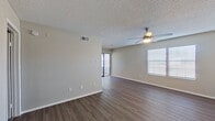 This single-story unit offers a practical and well-organized layout across three bedrooms and two bathrooms. The living room serves as the central gathering space, featuring wood-style plank flooring, neutral-toned walls, a textured ceiling, and a ceiling fan with integrated lighting. Natural light filters in through multiple windows fitted with blinds, while a sliding glass door provides access to the outdoors. The entry door is equipped with a deadbolt for added security.

The kitchen is outfitted with white upper cabinetry, dark lower cabinets, light countertops, and a stainless steel dishwasher, providing a clean, modern aesthetic. The bedrooms are carpeted and include generous closets with multi-rod shelving systems for organized storage. The primary bedroom is a comfortable size, offering ample room for standard furnishings. One bedroom features large windows and light-toned wood-style flooring with a ceiling fan.

Both bathrooms include tub-shower combinations with white tile surrounds, dark vanity cabinetry, light countertops, and wood-style flooring. The overall aesthetic throughout is neutral and contemporary, creating a clean, move-in-ready environment.
