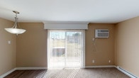 Located at 5107 Colerain Ave in Cincinnati, Ohio, this single-floor unit offers a practical and well-organized layout with a clean, neutral aesthetic throughout. The open-concept living and dining area is finished with warm beige walls, plush carpeting, and hardwood-style flooring at the entry transition. Large sliding glass doors dressed with vertical blinds flood the living space with natural light and provide access to an outdoor area, while a wall-mounted air conditioning unit ensures year-round comfort. A stylish pendant light fixture anchors the dining area, which also benefits from the abundance of natural light. The kitchen is efficiently designed and features dark espresso cabinetry with shaker-style doors, granite-look countertops, stainless steel appliances including a refrigerator and range, and durable hardwood-style flooring. A pass-through counter connects the kitchen to the living area, creating an open and connected feel. The bedroom is carpeted and offers a quiet, naturally lit retreat with a window overlooking greenery. The bathroom is neatly appointed with tile flooring, a full tub and shower combo with a curved curtain rod, and clean white fixtures. Overall, this space delivers a functional and comfortable living environment in a straightforward, well-maintained setting.