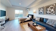 This efficiently designed studio suite at 169 Rutland N Rd in Kelowna, BC offers a well-planned single-floor layout that maximizes every square foot. The main living area serves as a combined sleeping and lounge space, finished with light-toned laminate flooring that runs throughout, creating a cohesive and open feel. A wall-mounted mini-split unit provides climate control, while a large sliding glass door floods the room with natural light and leads to a private balcony overlooking open surroundings.

The kitchen is thoughtfully designed with a galley-style configuration, featuring two-toned cabinetry — light wood uppers paired with grey lower cabinets — complemented by white quartz countertops and a classic subway tile backsplash. Stainless steel appliances, including a full-sized refrigerator, dishwasher, and electric range with an overhead exhaust hood, provide full functionality.

The bathroom maintains the same modern aesthetic, with a grey vanity cabinet, white quartz countertop, undermount sink, and light wood-look flooring. Recessed lighting and clean white walls complete the polished, contemporary finish found consistently throughout the suite.