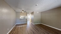 Located on E Speedway Blvd in Tucson, Arizona, this 2-bedroom, 2-bathroom single-story residence offers a functional and well-organized layout. The living room serves as the heart of the home, featuring rich dark wood-style vinyl flooring, a ceiling fan, and a textured ceiling. A pass-through counter connects the living area to the kitchen, which is equipped with white appliances and light wood cabinetry, creating an open and accessible feel. A hallway leads from the main living space to the bedrooms and bathrooms. Both bedrooms are carpeted and finished with neutral taupe-toned walls, offering a calm, restful atmosphere. Each bedroom includes a window that allows natural light to filter in, and closets provide practical storage. The primary bedroom includes its own en-suite bathroom featuring a stand-up shower with a sliding glass door, a single-sink vanity with light wood cabinetry, and wood-style flooring. The second bathroom mirrors a similar aesthetic, offering a bathtub/shower combination, a wide single-sink vanity, and matching finishes. Throughout the residence, consistent neutral tones, white trim, and textured ceilings create a cohesive and clean interior style well-suited to Tucson living.